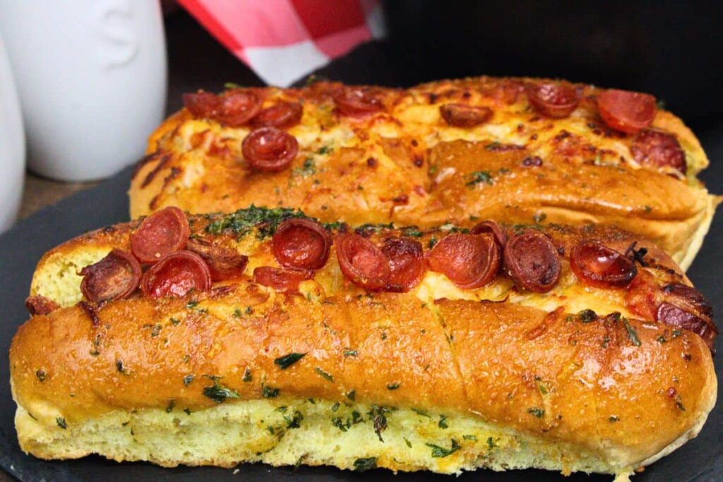 closeup of two pizza hot dogs topped with mini pepperoni and brushed with garlic butter