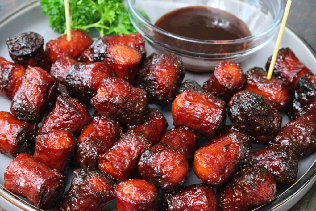 closeup view of hot dog burnt ends on a plate with bbq sauce for dipping