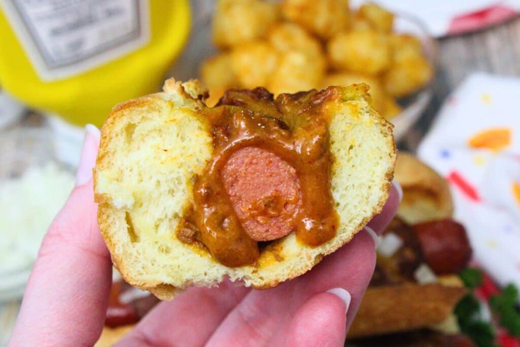 holding up half of a sonic chili cheese dog to show the chili dripping down the sides