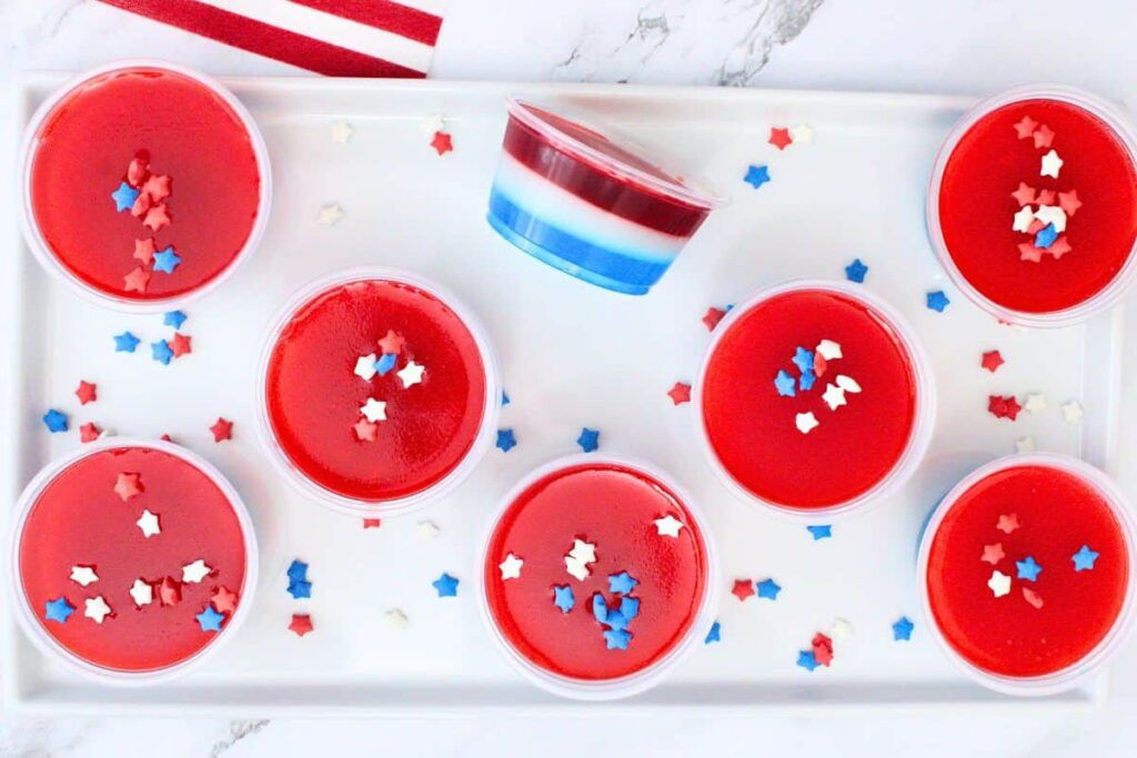 overhead view of red white and blue jello shots with one tipped on the side to show layers