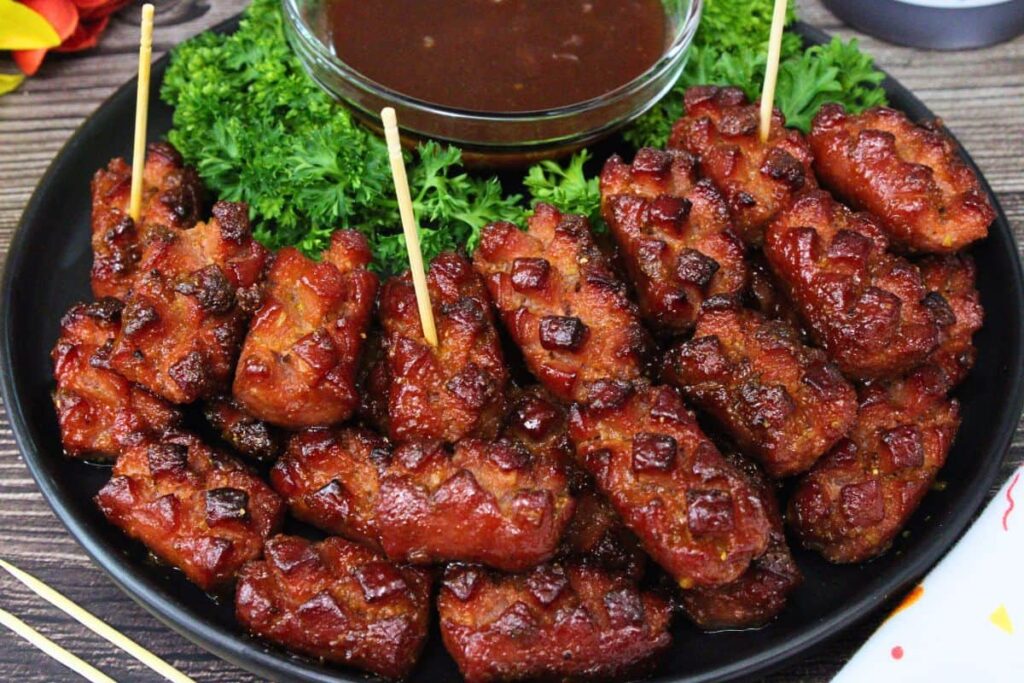 plate of air fryer hot dog pinecones on a black plate with a small dish of bbq sauce