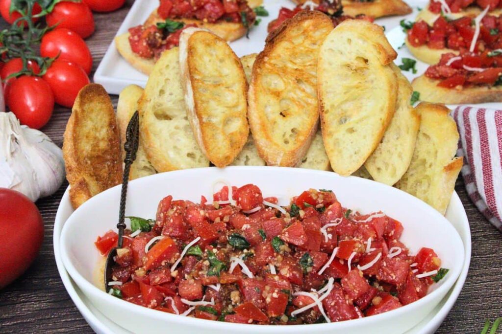bowl of bruschetta topping surrounded by toasted baguette