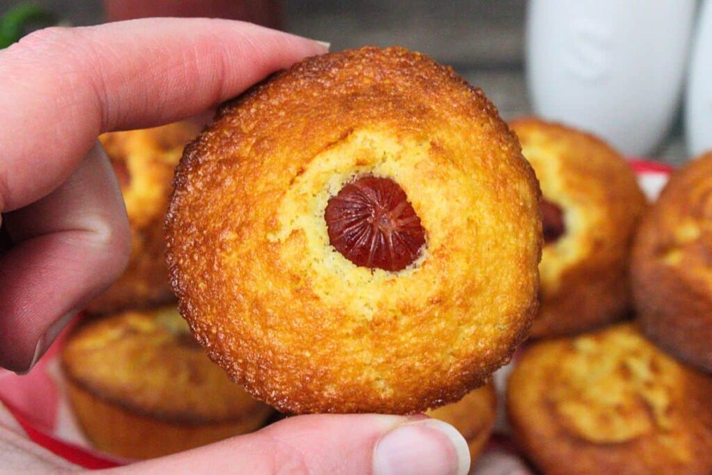 holding up an air fryer corn dog muffin showing the hot dog in the center