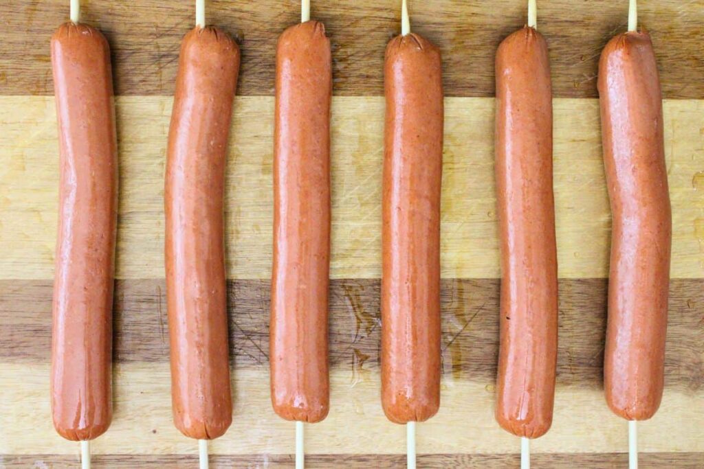 thread skewer lengthwise through hot dogs