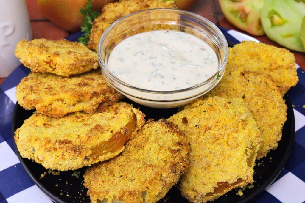 air fryer fried green tomatoes on a plate circling a bowl of hot honey ranch sauce