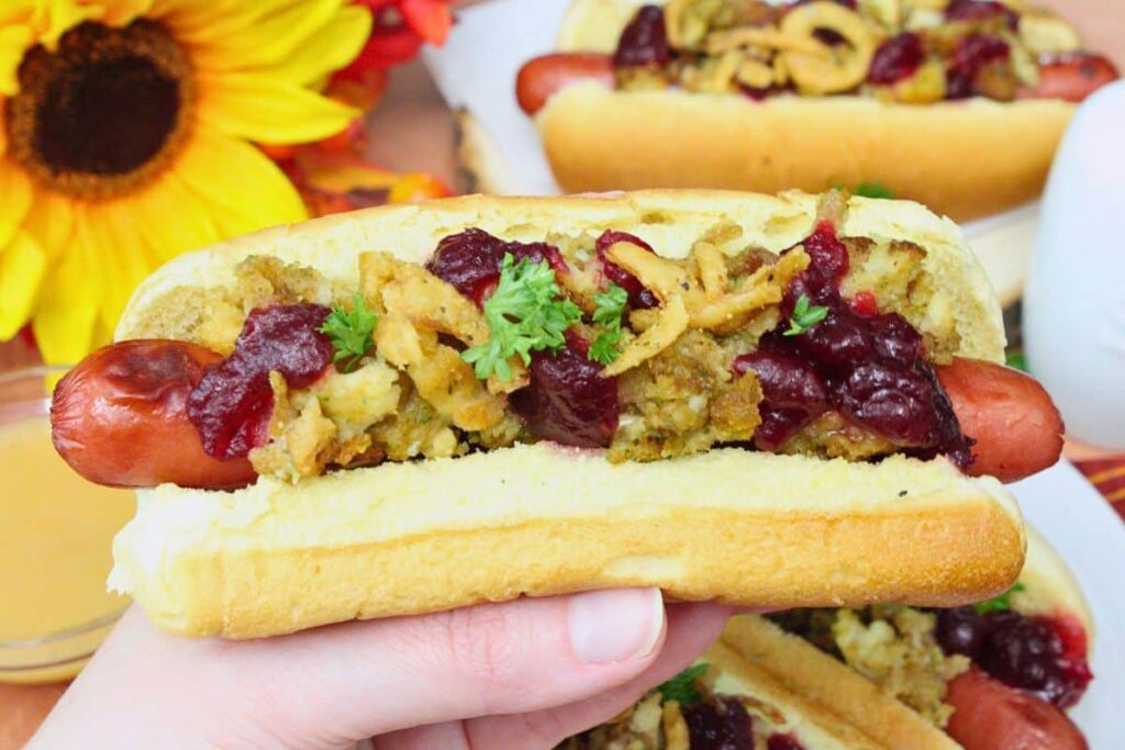 holding up an air fryer thanksgiving hot dog showing off the stuffing, cranberry sauce, and crispy fried onions