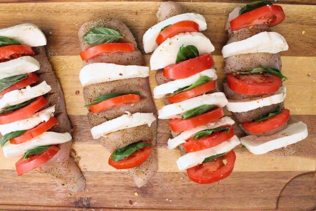 insert tomato, basil, and mozzarella in chicken slits
