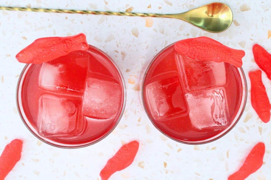 overhead view of two swedish fish cocktails surrounded by gummy fish and stirrer