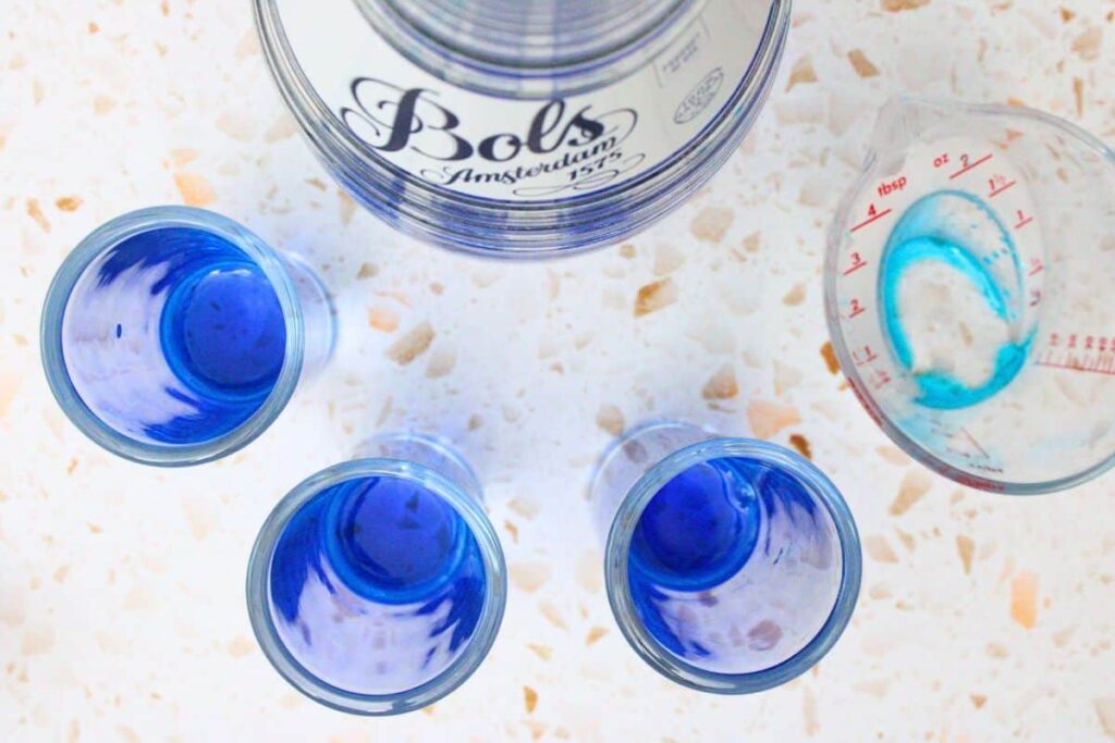 pour blue curacao into base of shot glasses