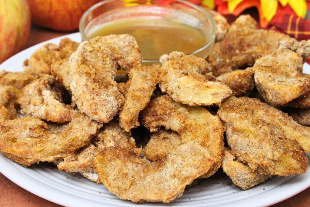 closeup view of air fryer apple fries on a plate in front of homemade salted caramel sauce