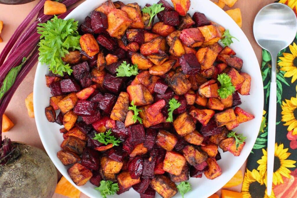 overhead view of air fryer beets and sweet potatoes on a plate with a serving spoon next to it