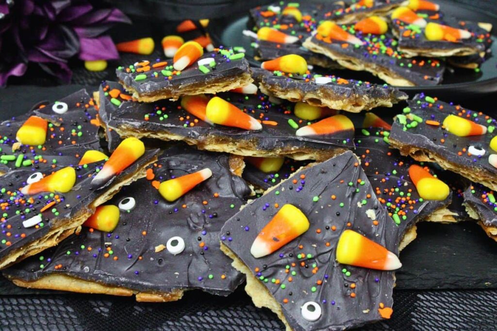 sweet halloween crack with candy corn and candy eyes overflowing on a black slate platter