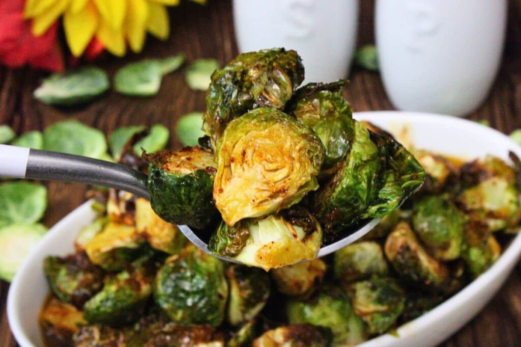 holding up a spoonful of air fryer longhorn brussel sprouts