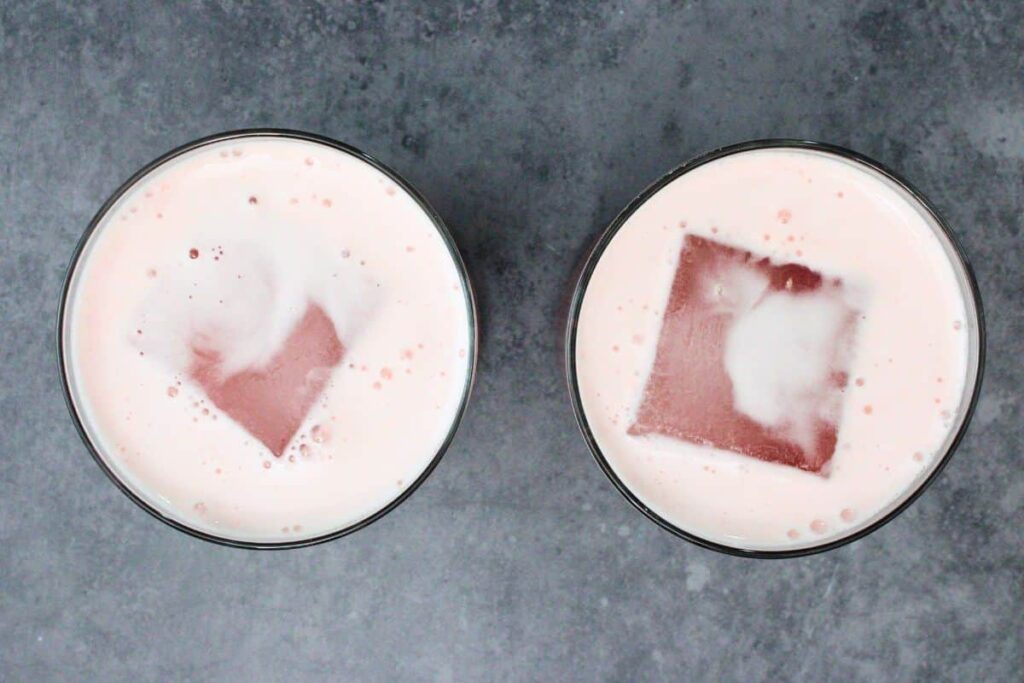 strain cranberry vodka sour into glass with ice