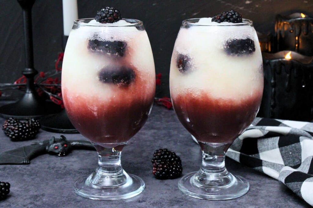 two applebees dracula juice cocktails side by side showing fresh blackberries inside layered red and white frozen drink