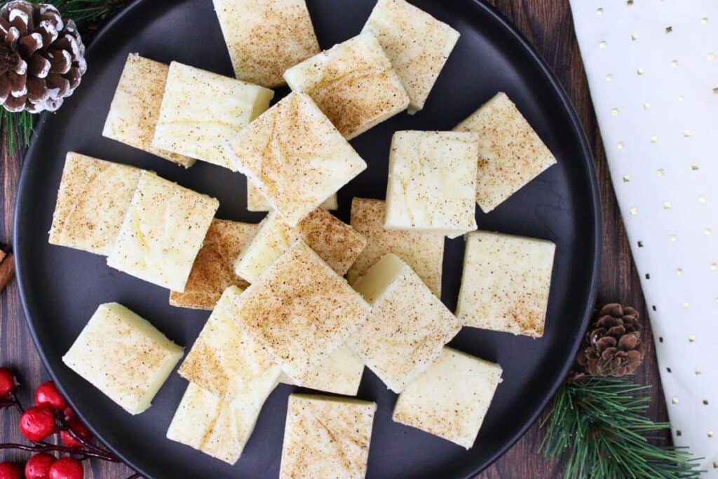 overhead view of eggnog fudge squares garnished with nutmeg on a black plate