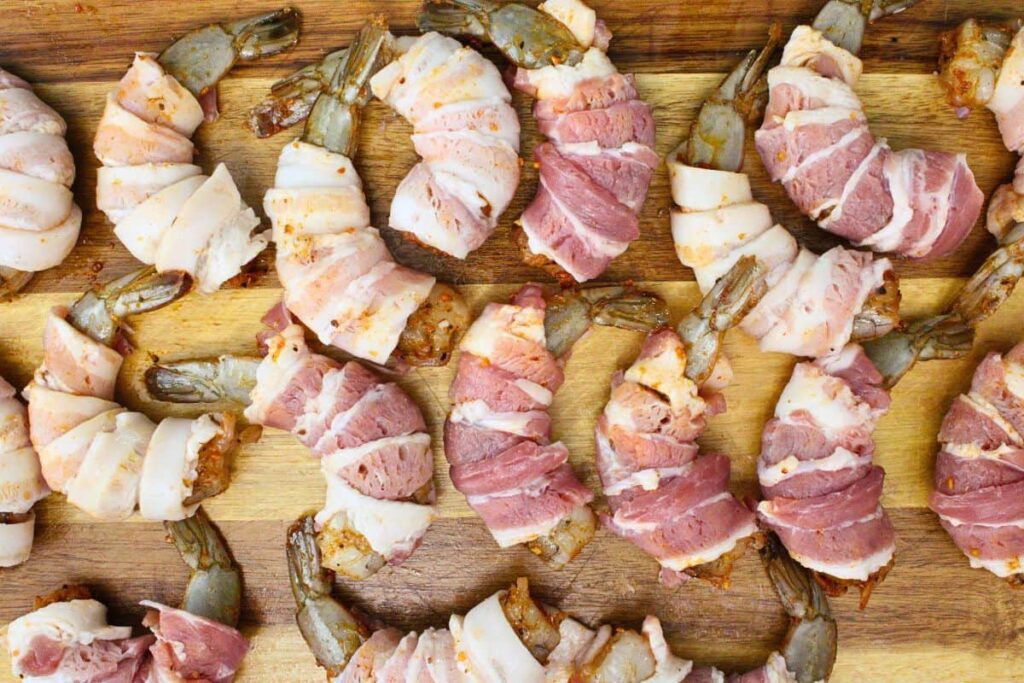 start at the tail and wrap a piece of bacon around each shrimp