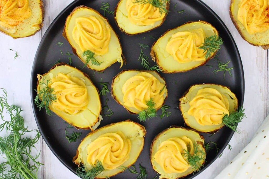overhead view of air fryer deviled potatoes garnished with paprika and dill on a black plate and white wooden table