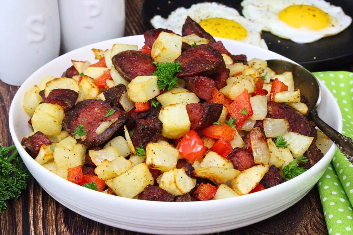 bowl of kielbasa hash with potatoes, peppers, and onions plus two sunny side up eggs