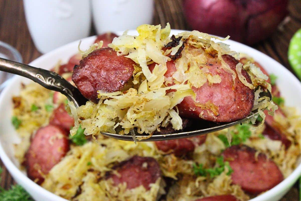 holding up a forkful of air fryer kielbasa and sauerkraut