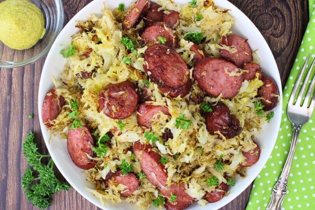 overhead view of kielbasa and sauerkraut pile up on a plate sitting on a wooden table