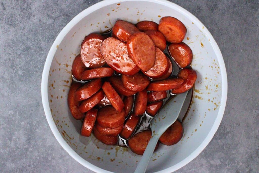 add cooked kielbasa to bbq jelly glaze and mix