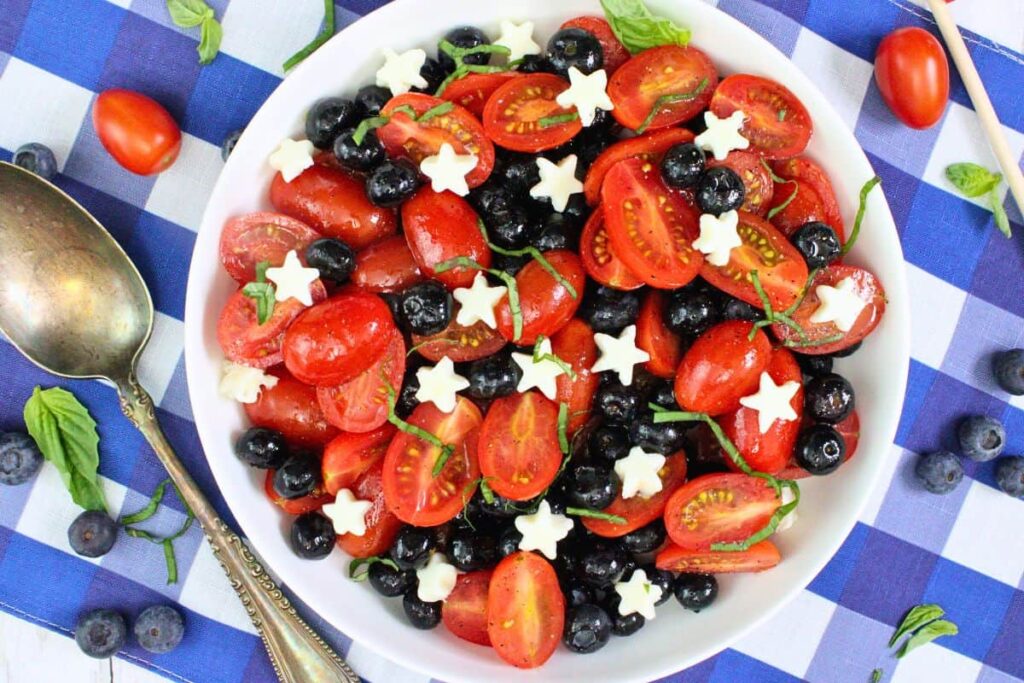 overhead view of red white and blue caprese salad showing off cherry tomatoes, blueberries, and star shaped mozzarella