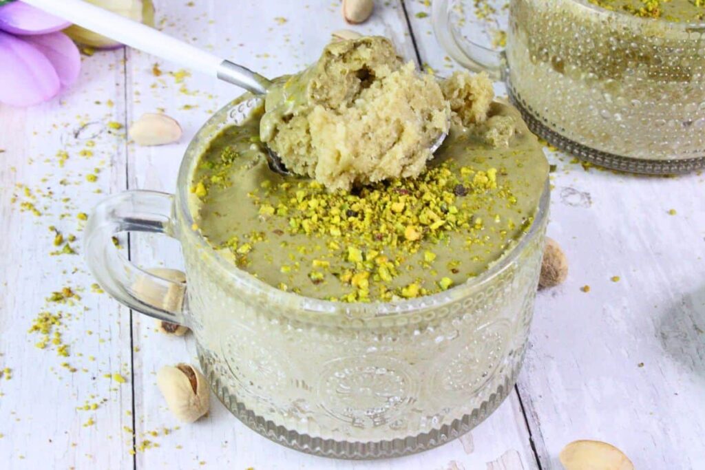 single serve pistachio mug cake with a spoon scooping out the middle