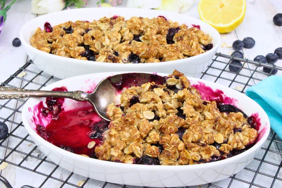 two air fryer blueberry crisps with one serving spoon scooping more of the dessert