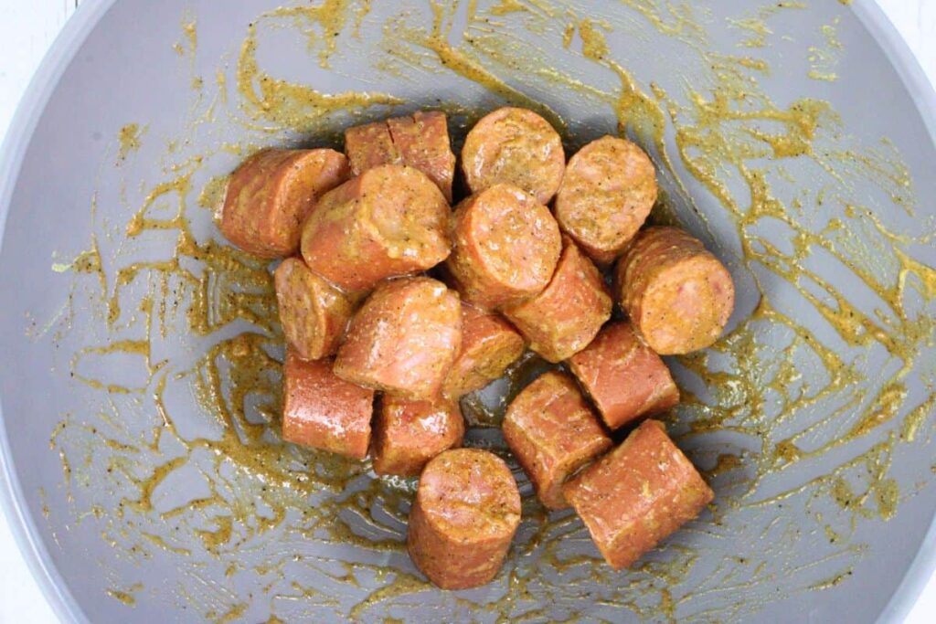 add scored kielbasa to a bowl with glaze to coat