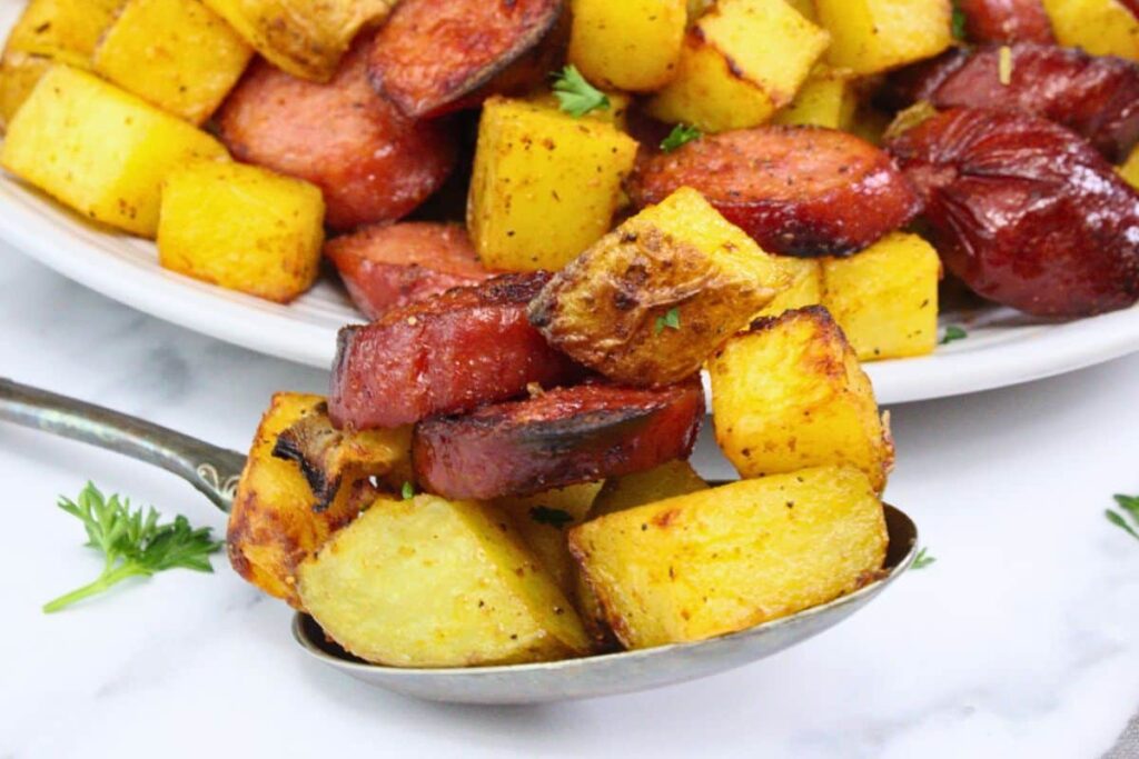 closeup view of spoon filled with air fryer kielbasa and potatoes