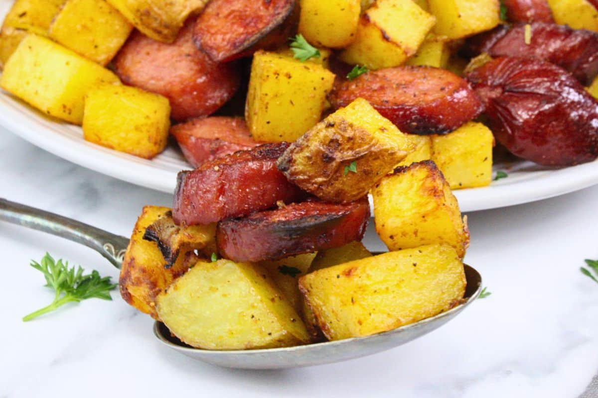closeup view of spoon filled with air fryer kielbasa and potatoes