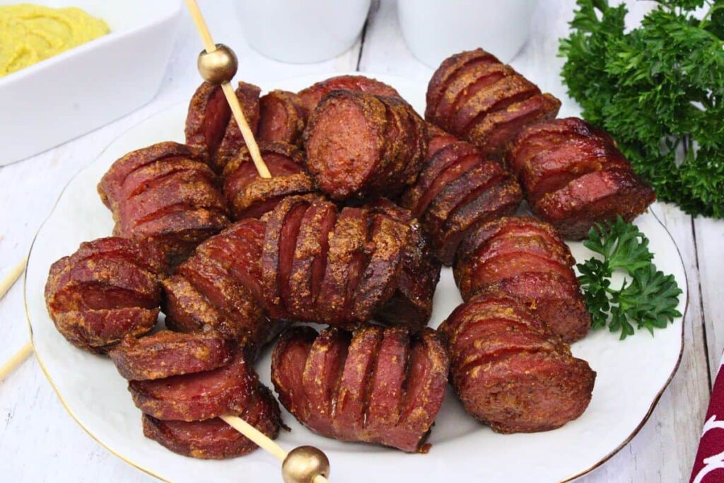 hasselback kielbasa bites on a plate with toothpicks and fresh parsley