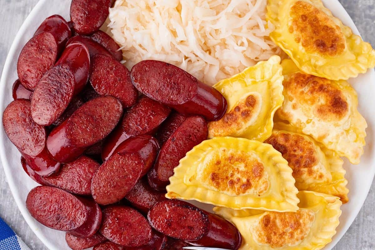overhead view of air fryer kielbasa on a plate with pierogies and sauerkraut