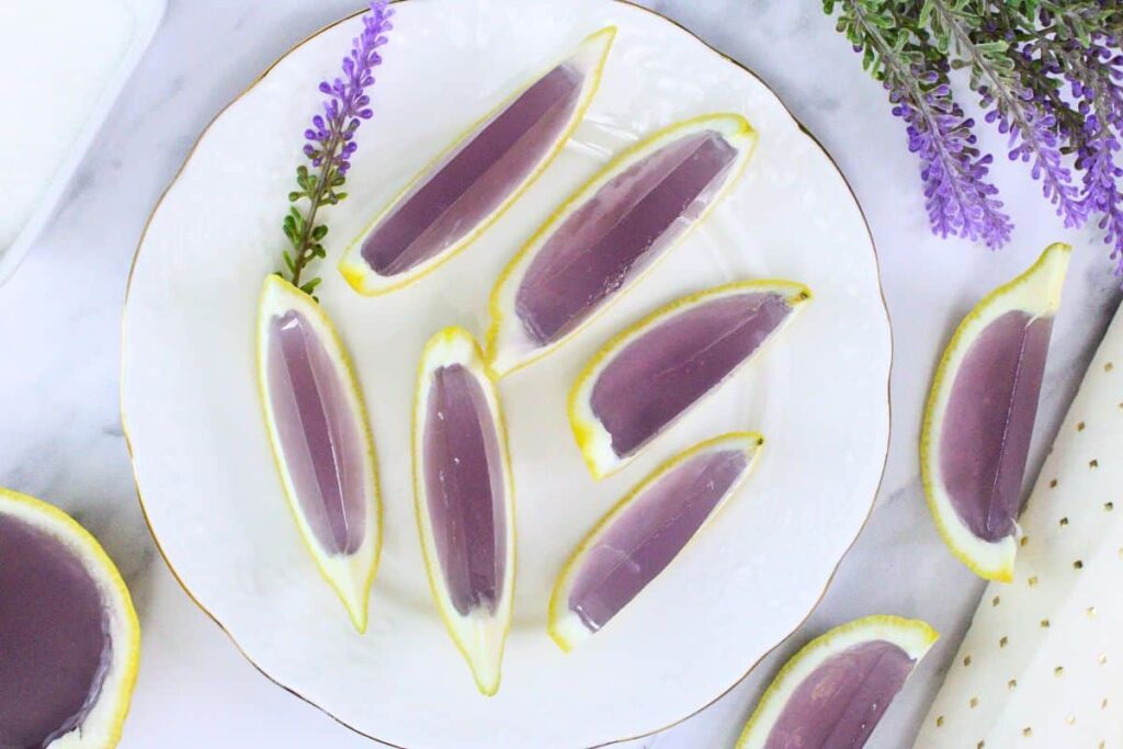 overhead view of lavender lemonade jello shots in lemon rinds on a white plate