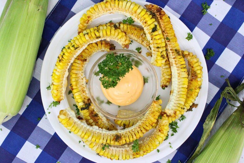 overhead view of corn ribs with cajun butter circling a plate with sauce in the middle