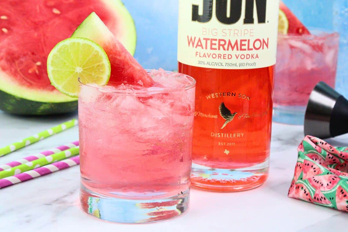 watermelon crush drink with fresh lime wheel and watermelon garnish next to vodka bottle