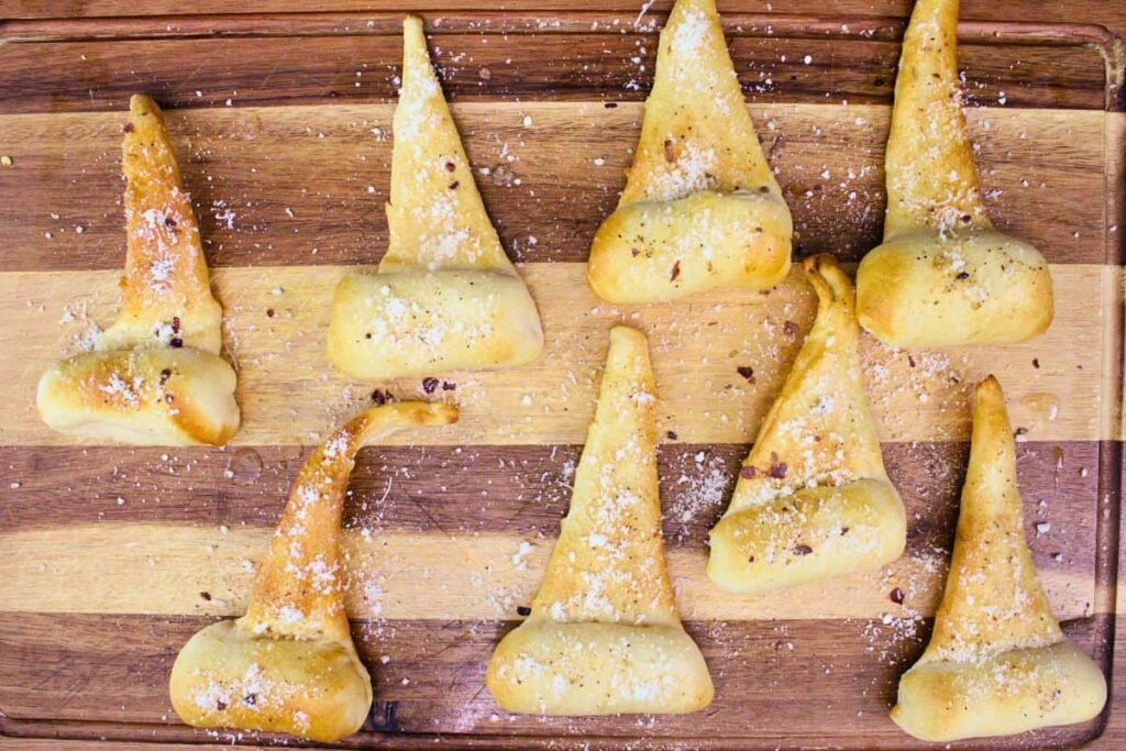 brush cooked crescent roll witch hats with butter and sprinkle parmesan and seasonings