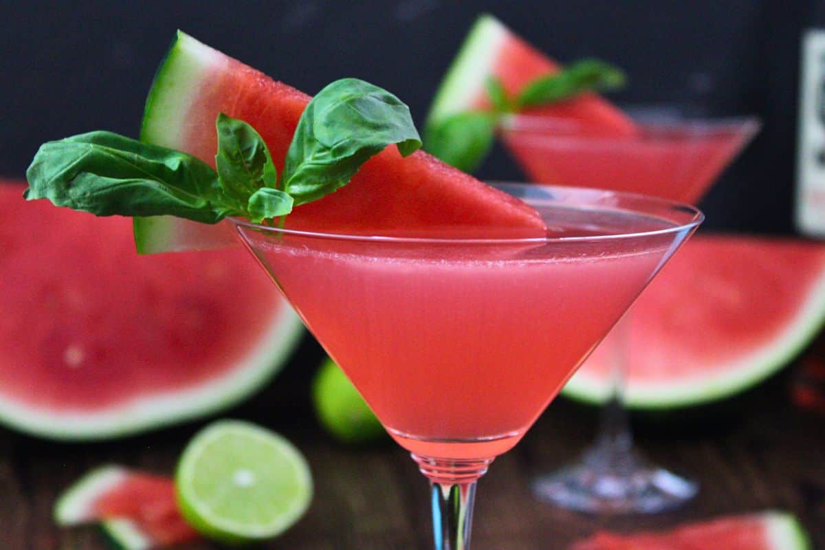 closeup view of chilled watermelon martini garnished with watermelon wedge and fresh basil