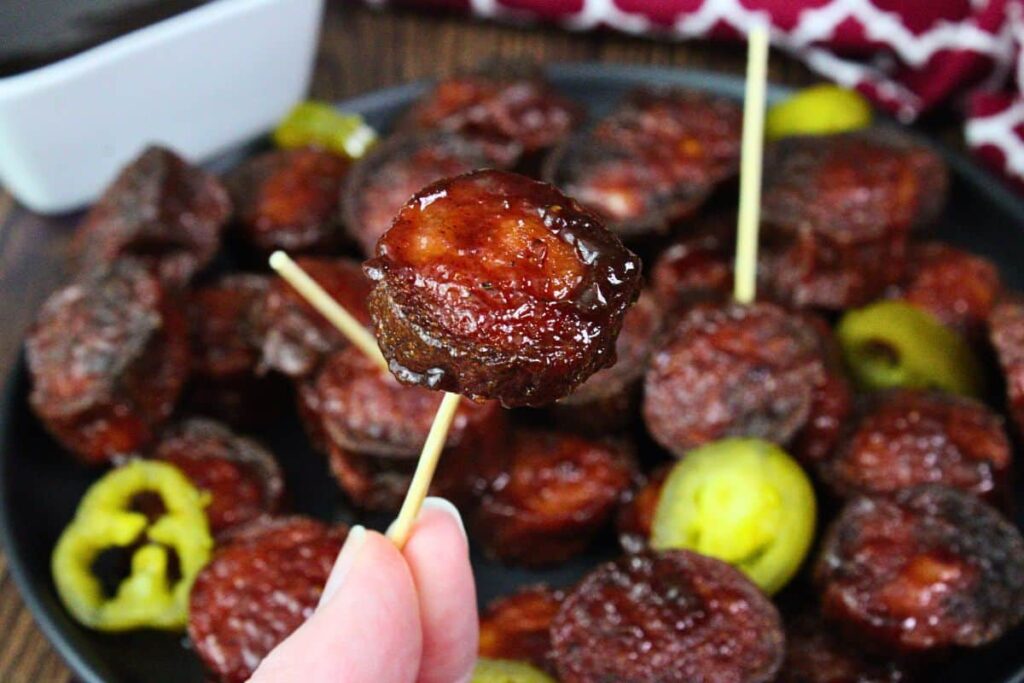 holding up a bbq kielbasa burnt end on a toothpick