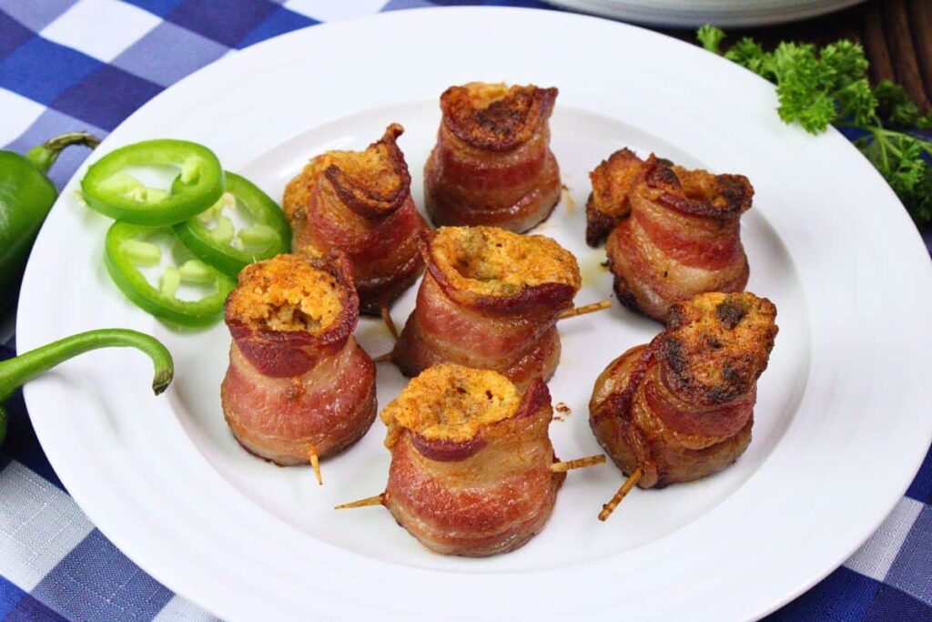 plate of air fryer pig shots showing off cheesy filling and bacon next to fresh jalapenos