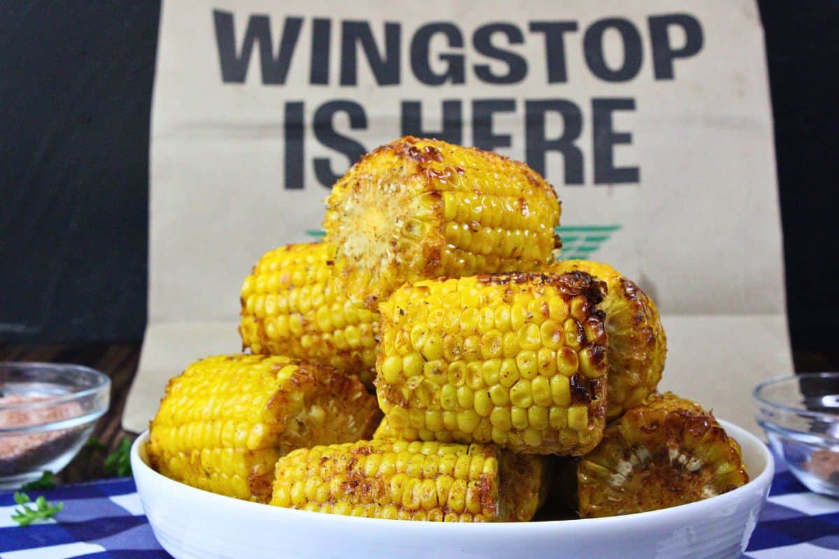 plate stacked with buttery cajun wingstop corn in front of wingstop bag