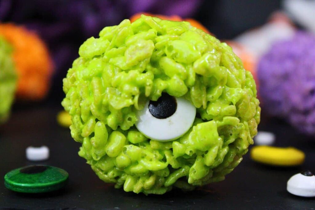 closeup of green monster rice krispie treat with large candy eye on piece of slate
