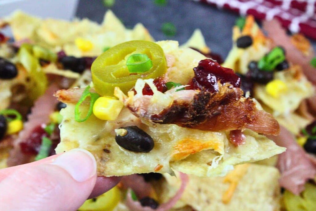 holding up a turkey nacho chip showing off the loaded toppings