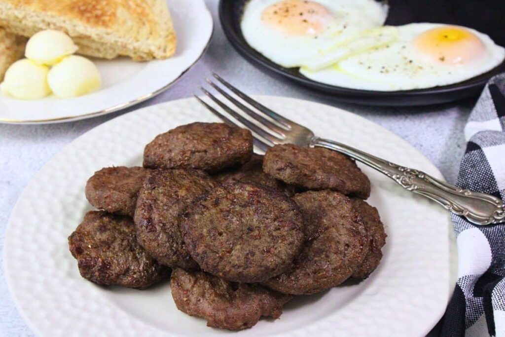 looking down at a plate of air fryer turkey breakfast sausage with a fork in front of eggs and toast