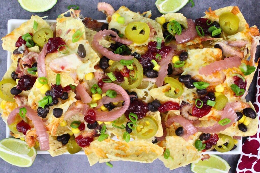 overhead view of air fryer turkey nachos on a platter with jalapenos, pickled red onions, corn, black beans, and cranberry relish