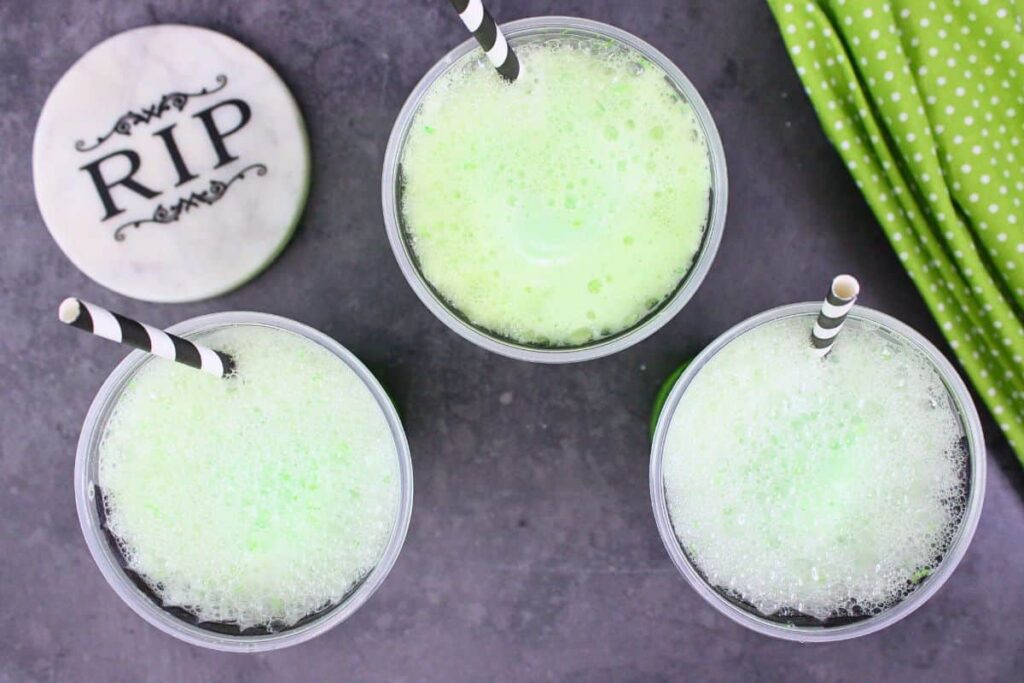 overhead view of three frankenstein floats with black striped straws and halloween coasters