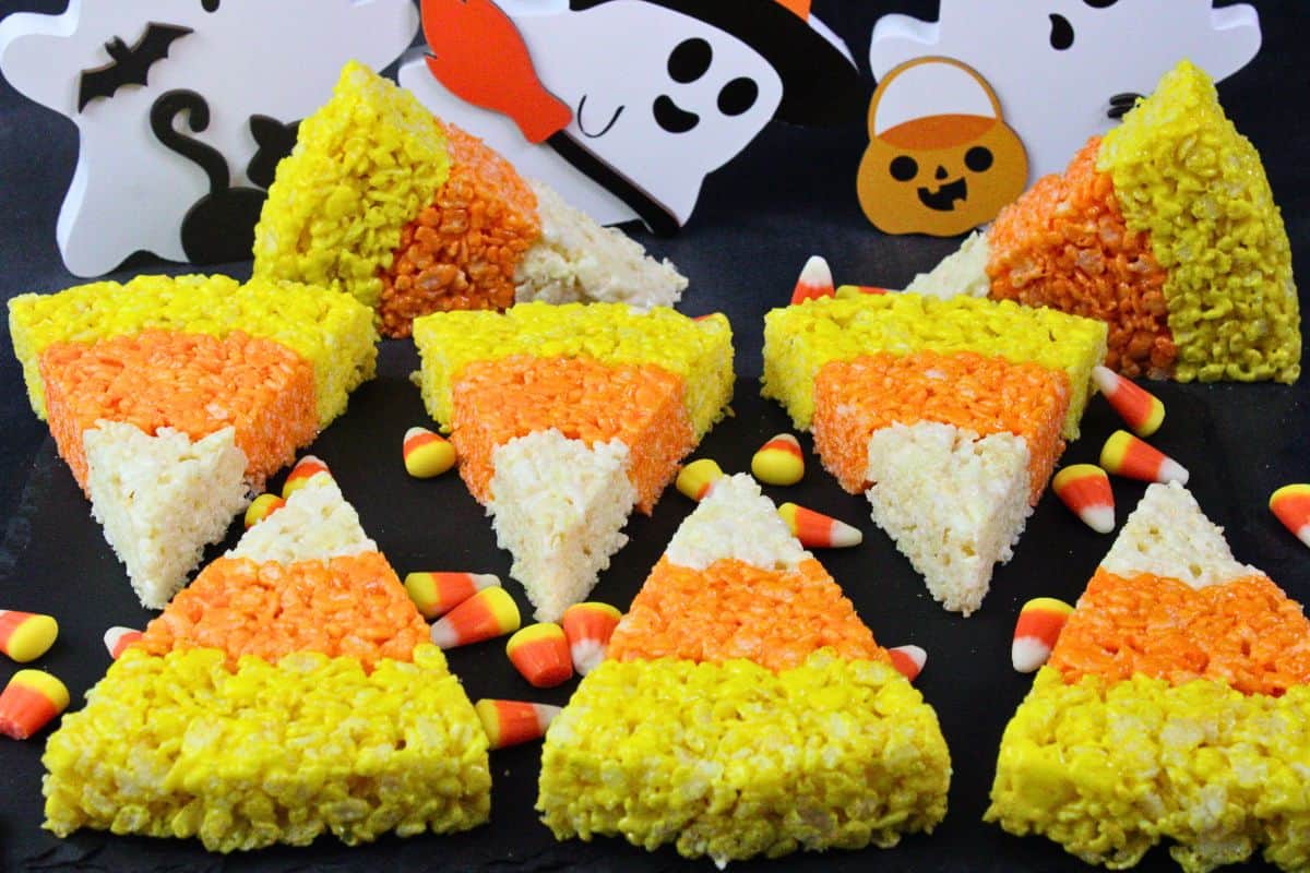 several candy corn rice krispie treats on black slate surrounded by candy