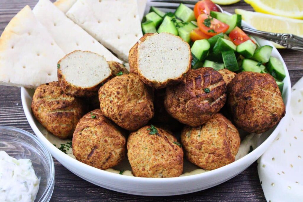 shallow bowl with air fryer trader joes turkey meatballs and pita wedges with one meatball cut in half