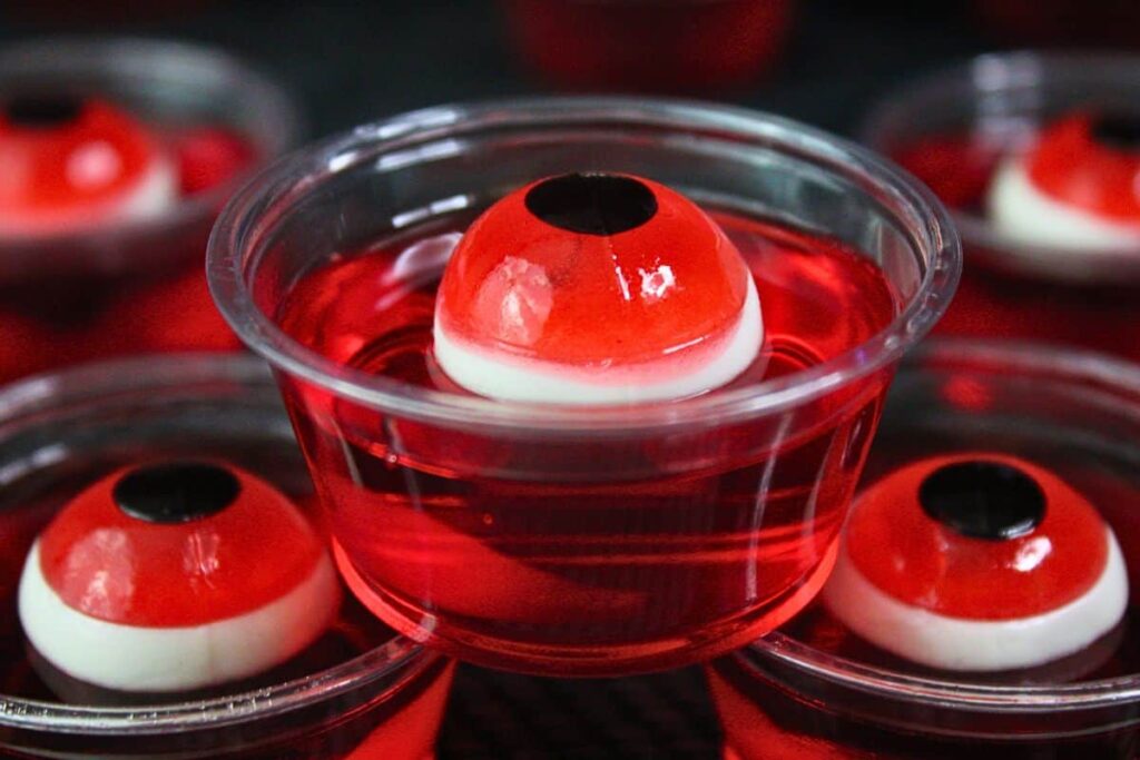 dramatic closeup view of three eyeball jello shots with red gummy eyes